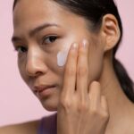 Contact Close-up of a woman applying skincare cream indoors.
